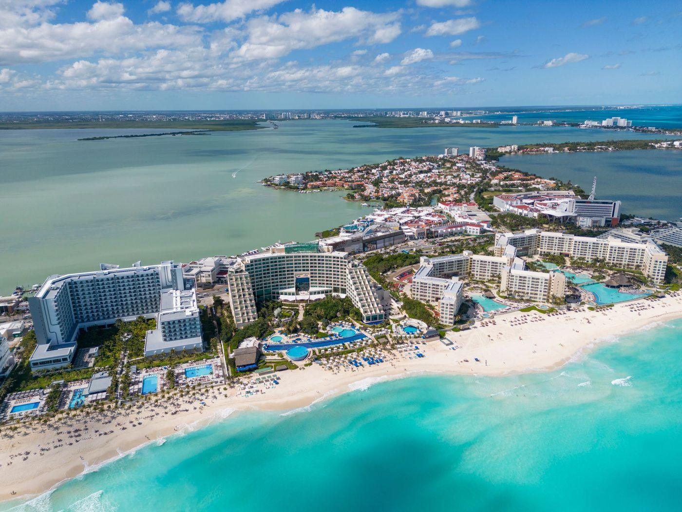 Resort hotels lined along a turquoise shoreline, seen from directly above